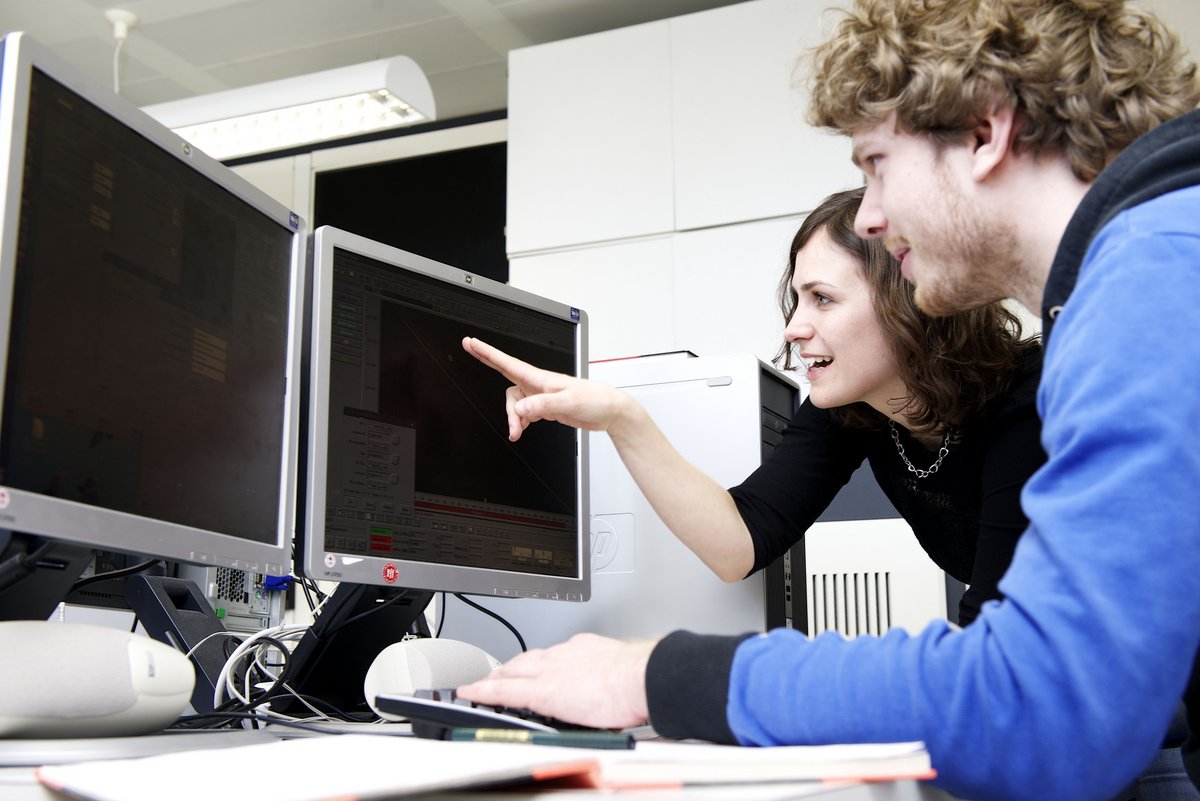 Eine Frau und ein Mann betrachten gemeinsam Forschungsdaten an einem Computer
