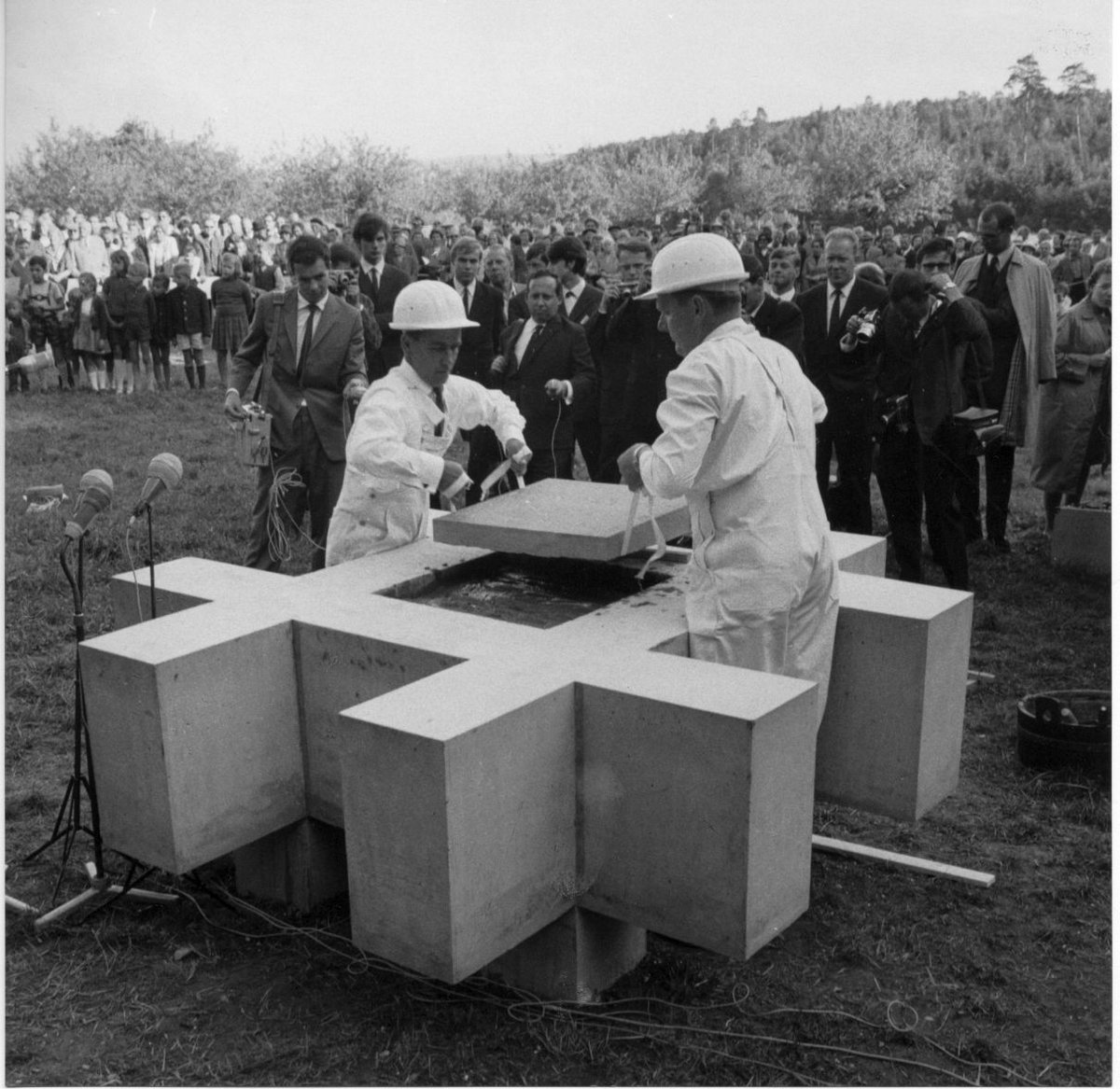 Two people in white coats lay the last stone of the foundation stone