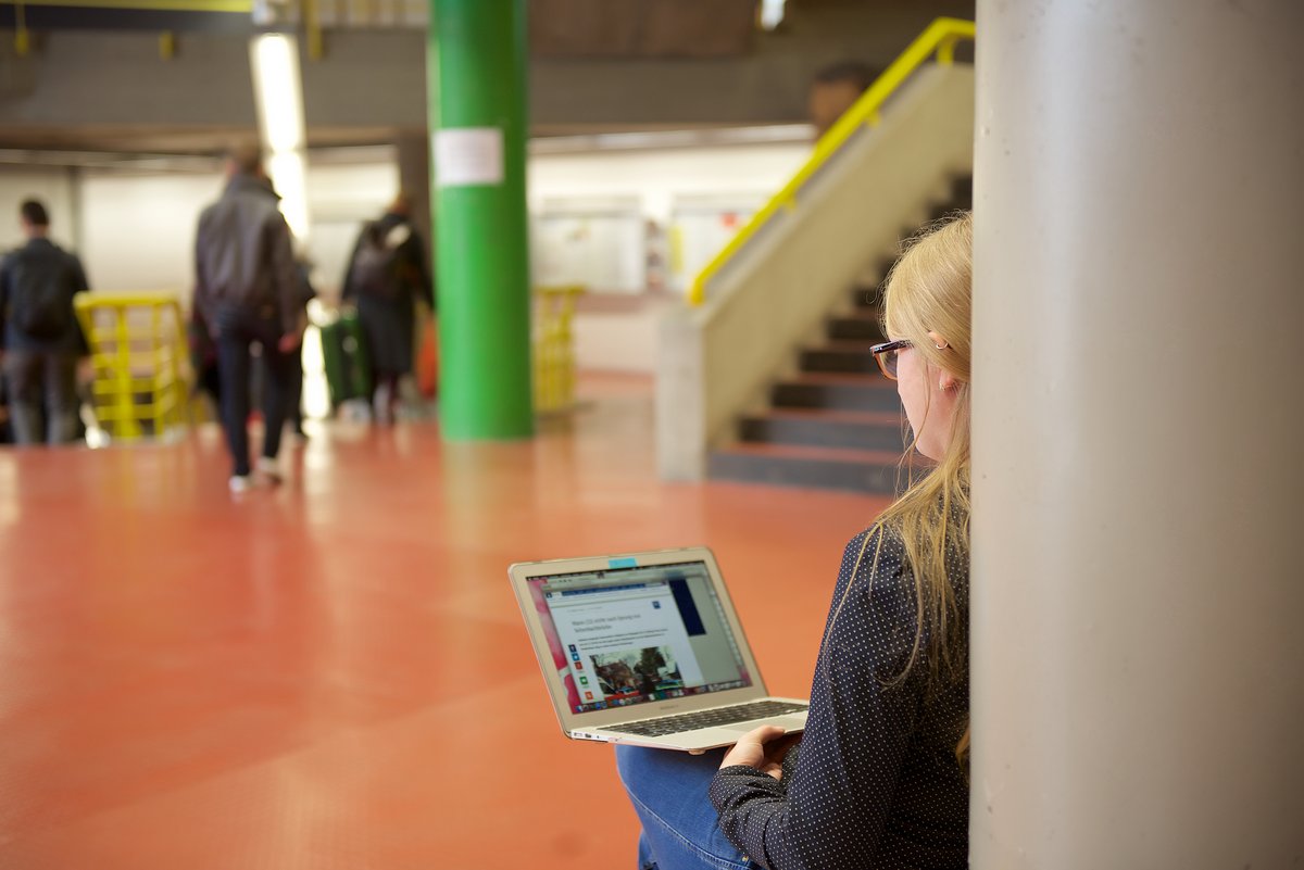 student in the foyer using her laptop